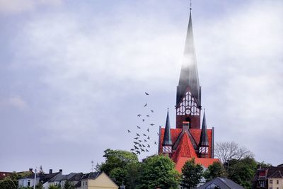 Low angle view of church in town against cloudy sky