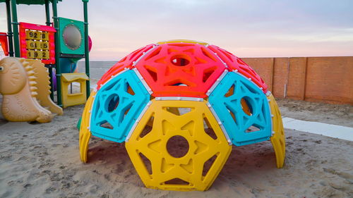 Multi colored toy on sand at beach against sky