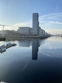 Reflection of buildings in river against sky in city