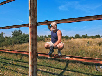 Athletic man sitting on a metal beam on nature