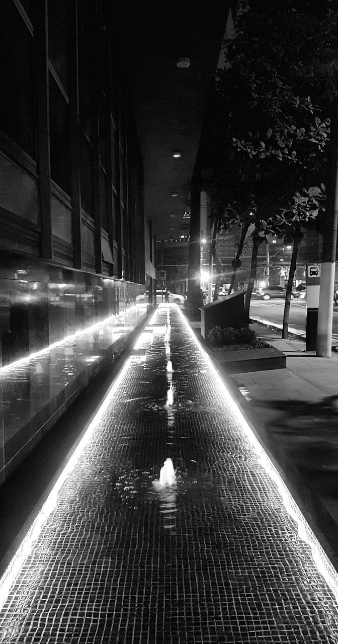 ILLUMINATED STREET AMIDST BUILDINGS AT NIGHT