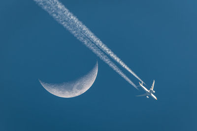 Low angle view of airplane flying against clear blue sky