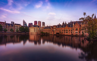 Buildings by river against sky in city