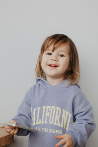 Portrait of cute girl standing against wall