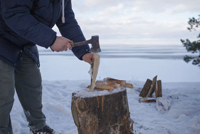 Low section of man breaking firewood during winter