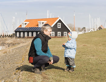 Full length of grandfather and granddaughter on field