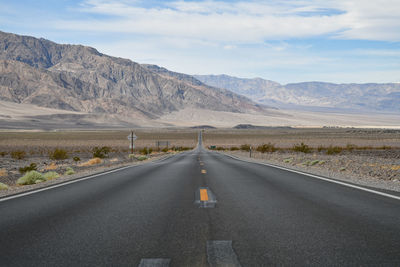 Empty road by mountains against sky