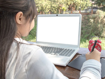 Midsection of woman using mobile phone while sitting on table