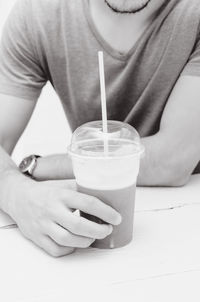 Midsection of man drinking glass on table