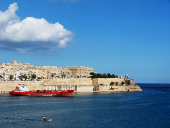 Buildings by sea against blue sky
