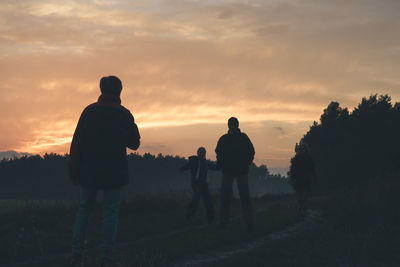 Rear view of silhouette men against sky during sunset