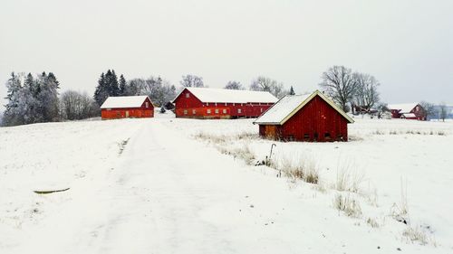 Houses on snow covered field against clear sky