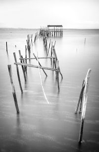 Wooden posts in sea against sky