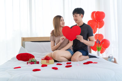 Couple kissing in heart shape on bed