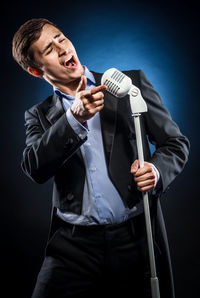 Opera singer singing while standing against black background