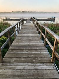 Wooden footbridge over pier against sky