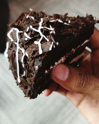 Close-up of hand holding chocolate cake