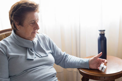 Senior caucasian woman over 70 using a pulse oximeter at home near a window
