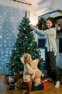 Full length of woman standing by christmas tree