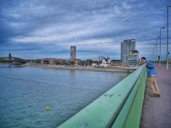 Man standing on bridge over river rhine in city against sky