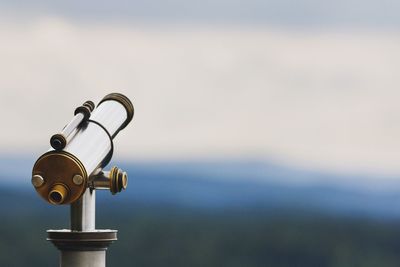 Close-up of coin-operated binoculars by sea against sky