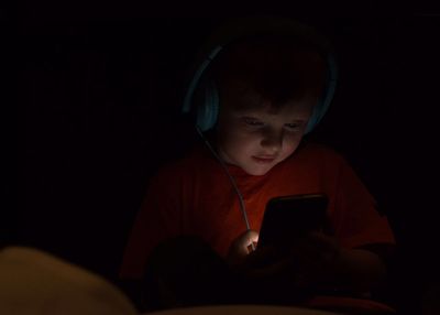 Boy using mobile phone in darkroom