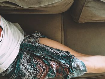 Midsection of woman relaxing on sofa at home