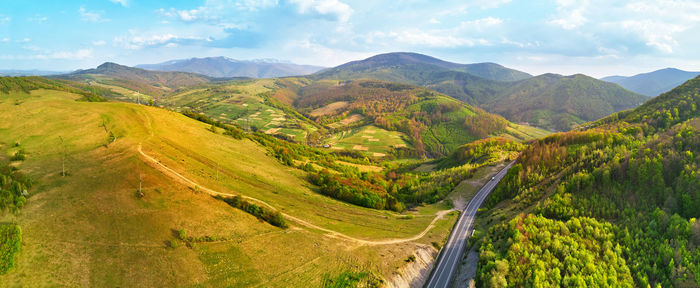 Highway in mountains. evening sunlight on hills. spring green rural landscape. aerial view on road