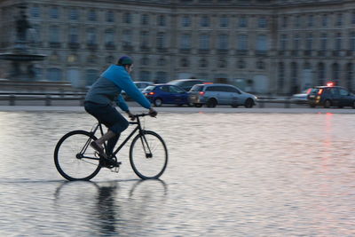 Man riding bicycle on road in city