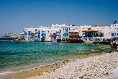 Sea by buildings against clear blue sky