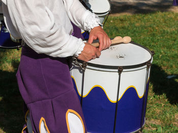 Midsection of man playing drum while standing outdoors