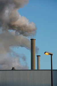 Low angle view of smoke emitting from chimney against sky