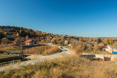High angle view of houses on field against clear blue sky