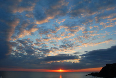 Scenic view of sea against cloudy sky at sunset