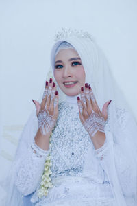 Portrait of smiling young woman wearing hijab against white background