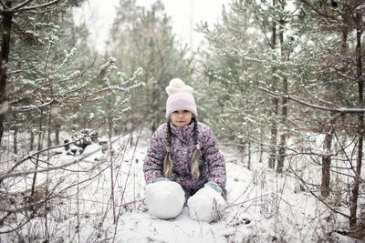 Cute girl sitting on snow covered land