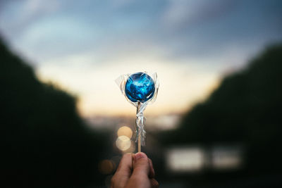 Close-up of hand holding bubble against sky