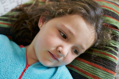 Girl thinking and resting on soft striped pillow on couch at home