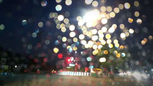 Defocused image of illuminated lights on street in city at night