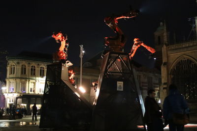 Statue in illuminated city against sky at night