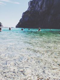 People swimming in sea against mountains