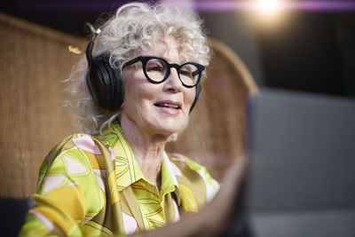 Senior woman in headphones using tablet