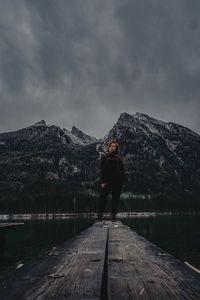Young girl standing on mountain by lake against sky