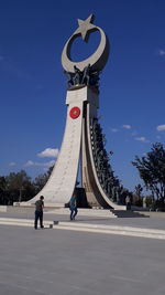 People walking in city against blue sky