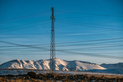 Electric pole against mountains