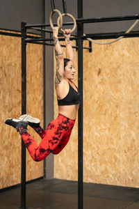 Full length of young woman exercising in gym