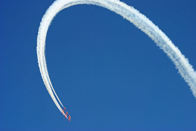 Low angle view of airplane flying against clear blue sky