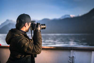 Side view of man photographing sea with digital camera