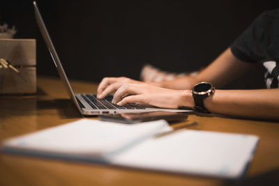 Cropped hands of woman using laptop at table