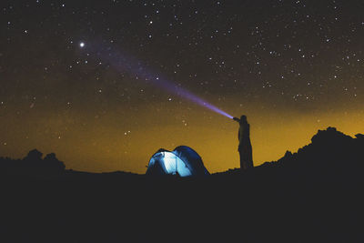 Rear view of woman standing against sky at night